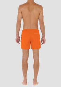 Oranssit uimapuvut, joissa on joustava vyötärönauha, takatasku ja sileä pinta. Keskipituinen, reiden puoliväliin asti ulottuva pituus, jossa on minimaalinen yksityiskohtaisuus.