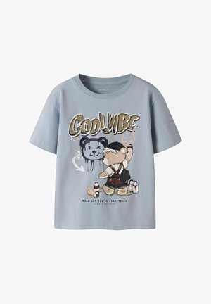 Camiseta infantil azul claro con un osito pintando con spray la cara de un oso negro y el texto "Cool Vibe" y "Will get you do everything."