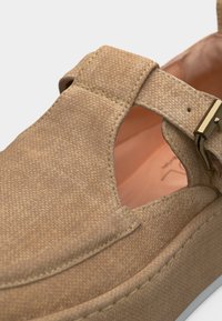 Sandale à plateforme beige texturée avec une bride à boucle dorée et une semelle intérieure en cuir marron clair.