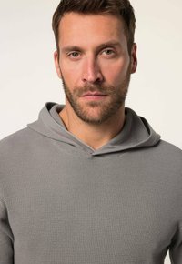Grau strukturierter Kapuzenpullover mit Kordelzug, der eine lockere Passform und ein weiches, gewebtes Aussehen aufweist. Auffällig durch seinen warmen Stoff und das dezente Design.