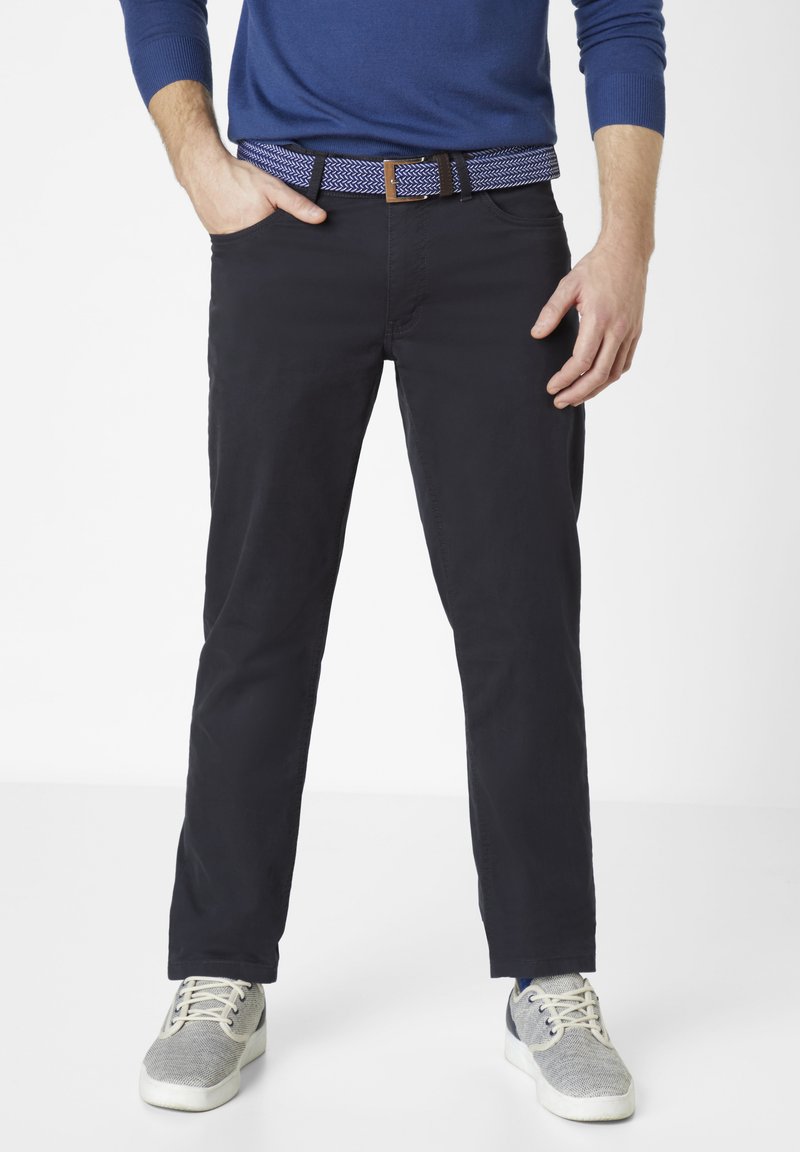 Men's navy chinos with a slim fit, paired with a patterned blue belt and grey sneakers. Smooth fabric with pockets and a casual design.