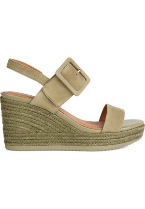 Sandalia cuña de color verde oliva con puntera redonda, material de ante, correa ajustable con hebilla y textura de media suela de yute trenzado.