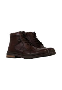 Bottes chelsea en cuir marron avec bout rond, lacets noirs, petits accents métalliques et un talon empilé. Surface texturée avec des coutures visibles.