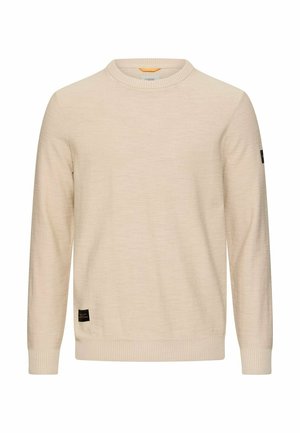 Beige langærmet sweater med rund hals, ribstrikkede manchetter og kant, med små sorte mærkepatches på nederste front og venstre ærme.