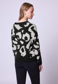 Maglione nero e crema lavorato a maglia con un audace design a stampa animale, collo rotondo, maniche lunghe e una finitura morbida e strutturata.
