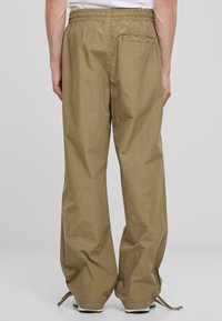 Khaki cargo bukser med elastisk talje, vide ben og en baglomme. Stoffet ser let og let tekstureret ud. Snoretræk i kanten.