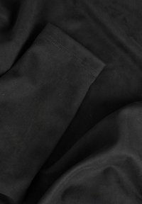 Svart stoff med en glatt, myk tekstur; viser en brettet kant med rene sting. Overflaten er rynkefri og ensartet.