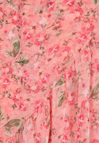 Stof met bloemendessin met roze en perzikkleurige bloemen op een lichtroze achtergrond. Fijne, lichte textuur met groene bladeren.