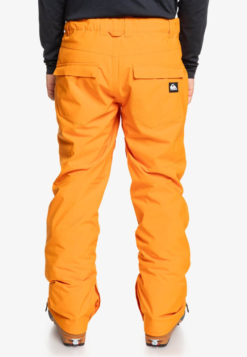 Pomarańczowe spodnie narciarskie o luźnym kroju, wykonane z wodoodpornego materiału. Posiadają podwójne tylne kieszenie oraz wzmocnione wykończenia dla większej trwałości.