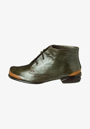Stivale alla caviglia in pelle verde con punta arrotondata, chiusura con lacci, decorazione in legno sul tacco e dettagli di cucitura a vista. Texture liscia in tutto il prodotto.