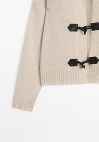 Beige knitted cardigan featuring a ribbed hem and sleeves, fastened with black toggle closures for secure fit and style.