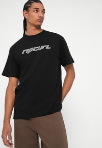 Black cotton t-shirt featuring the "Ripcurl" logo in white on the front, short sleeves, and a relaxed fit.