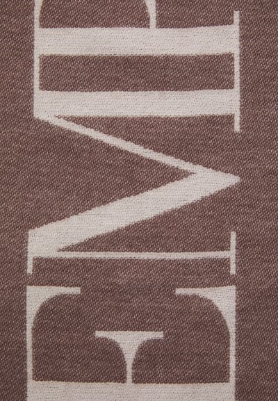 Tissu avec un fond marron, présentant un grand design géométrique blanc qui inclut des lettres et des formes, mettant en évidence le contraste et la texture.