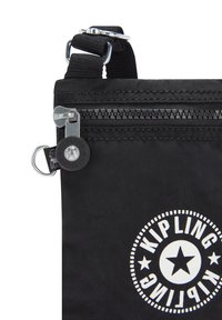 Černá textilní taška se zipem, s kulatým logem Kipling a designem hvězdy, obsahuje stříbrný zip. Součástí je nastavitelné ramenní pouzdro.