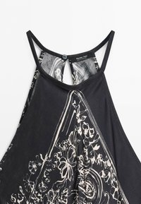 Zwarte mouwloze jurk met dunne bandjes en witte bloemen- en paisleyprint, knoopsluiting aan de achterkant, label met Massimo Dutti.