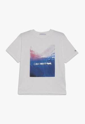 Biały T-shirt z krótkim rękawem z kolorową grafiką powierzchni oceanu i napisem "Calvin Klein Jeans" umieszczonym na środku przodu.