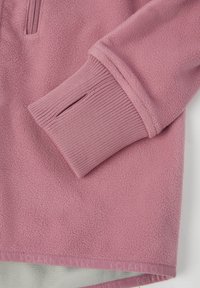 Fleece kledingstuk in zachtroze met ribgebreide boorden en zoom. Heeft een half-rits sluiting en een logoband aan de onderrand.