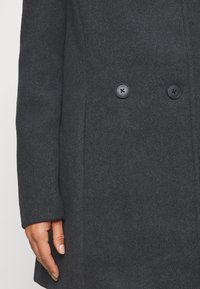 Szary płaszcz z wełny z prostym krojem, z dwoma czarnymi guzikami, subtelną teksturą oraz kieszenią po lewej stronie.