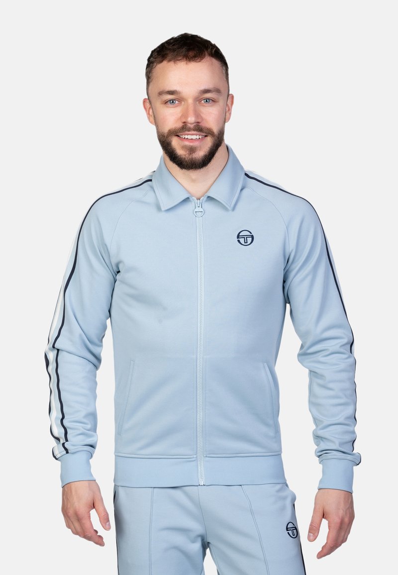 Helle blaue Zip-Jacke mit Kragen, ausgestattet mit schwarzen Seitenstreifen und Logo. Slim Fit mit gerippten Bündchen und Taschen.