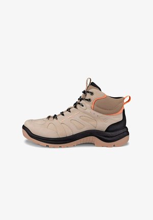 Beige vandrestøvle med sorte og orange detaljer. Har mesh-paneler, en polstret sål og flere øjer til snørebånd. Tekstureret overflade.