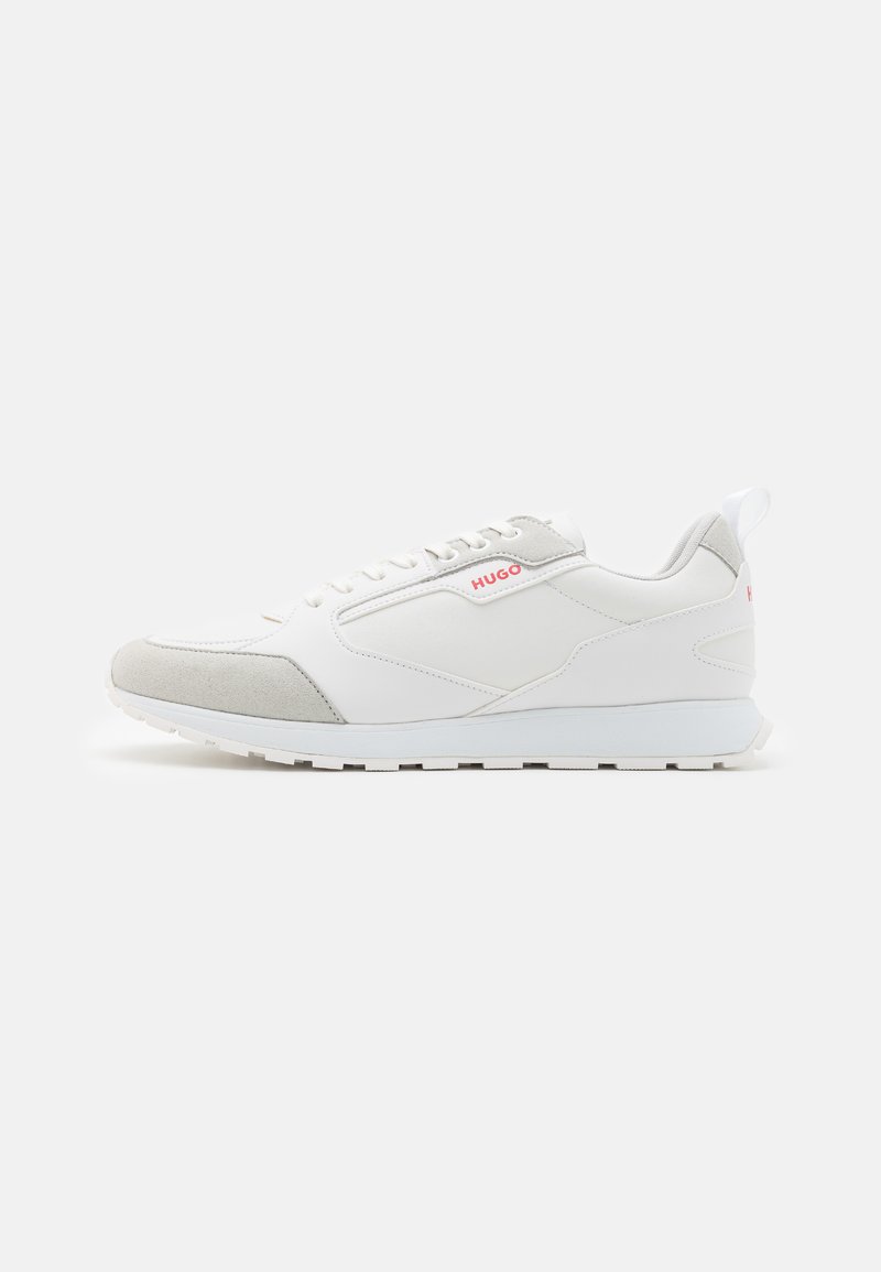 Hvite og lysegrå sneakers med en glatt lær overdel og saueaksenter, med en strukturert såle og minimal merkevare i rødt.