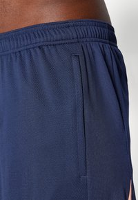 Pantalones cortos deportivos en color azul marino, hechos de tejido transpirable con un acabado texturizado, que cuentan con una cinturilla plana y bolsillos laterales.
