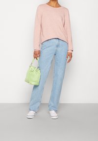 Ljusrosa långärmad tröja, högmidjade ljusblå jeans, vita sneakers och en liten grön hinkväska med dragsko.