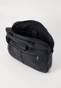 Sac en cuir noir avec un zip sur le dessus, plusieurs compartiments, design épuré et intérieur doublé en tissu. Comprend des poign�ées courtes et une poche extérieure.