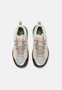 Beige hiking shoes with a breathable mesh upper, green accents, red and gray laces, black rubber soles, and a reinforced toe cap.