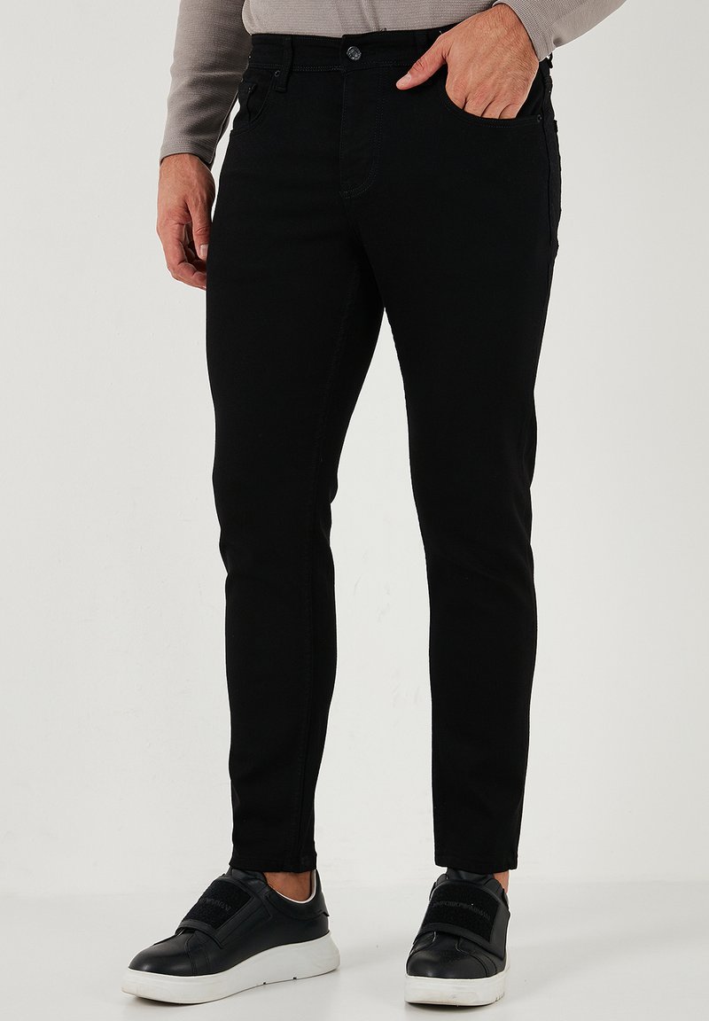 Svart smala jeans i en mjuk bomullsblandning. Har klassisk femfickorsdesign, framknäppning med knapp och subtila sömdekorationer.