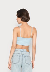 Top cropped azul claro com alças finas, combinado com jeans de cintura alta azul claro com um design clássico de cinco bolsos.