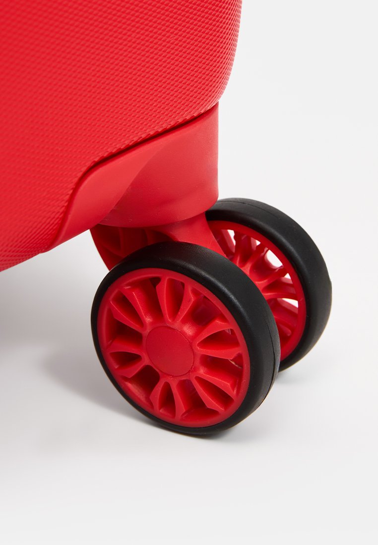 Roter Koffer mit strukturiertem Finish, ausgestattet mit geschmeidig rollenden schwarzen Rädern in Speichenform und roten Akzenten für eine einfache Mobilität.