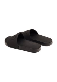 Black slide sandals with wide straps and textured footbed, featuring a smooth rubber material and subtle logo detail on the strap.