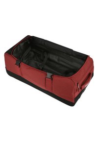 Bolsa de deporte roja con parte inferior negra, tejido texturizado, cierre de cremallera y correas interiores para asegurar los artículos. Forma rectangular, diseño espacioso.