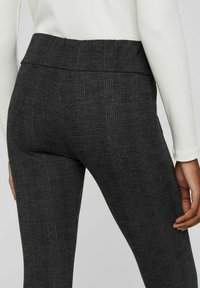 Leggings a scacchi neri con una texture liscia e una vita alta, caratterizzati da un design su misura per un look aderente.