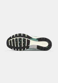 Nike tenisica s potplatom koji ima crnu gumenu podlogu, istaknuti uzorak gume, svjetloplave i bijele akcentne boje, te glatki, oblikovani dizajn.