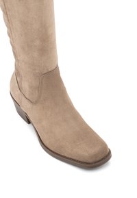 Knee-high beżowe zamszowe botki ze kwadratowym noskiem, lekko podwyższonym obcasem i tonowanymi przeszyciami. Miękka tekstura o gładkim wykończeniu.
