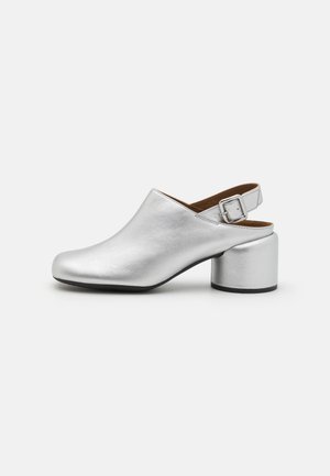 Silver leather high-heeled clogs with a rounded toe, tapered back, and adjustable buckle strap. Chunky, metallic block heel.
