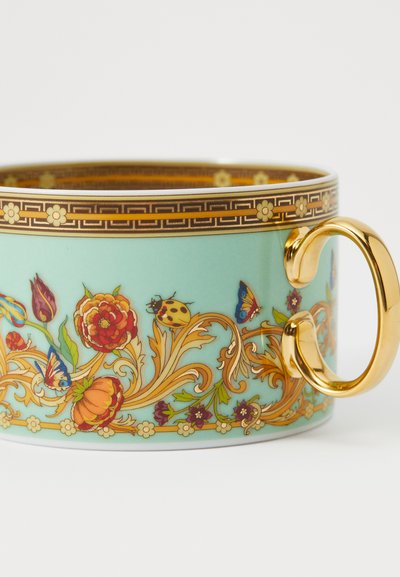 Keramiktasse in hellem Türkis, mit floralen und Insektenmotiven in lebendigen Farben. Goldene Akzente und Griff verstärken den verspielten Stil.