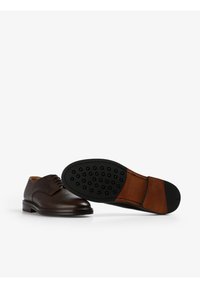 Braune Lederanzugschuhe mit strukturiertem Finish, runder Zehenform, Schnürdesign und Gummisohle mit kreisförmigen Grip-Mustern.