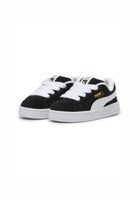 Baskets en daim noir avec des lacets blancs et des semelles en caoutchouc. Présente une rayure blanche Puma et un logo doré sur le côté. Détail de la semelle texturée.