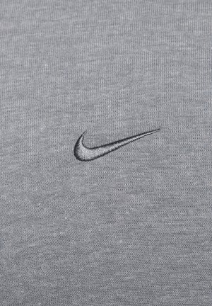 Gray fabric t-shirt with a textured knit pattern, featuring a black embroidered Nike swoosh logo on the left chest area.