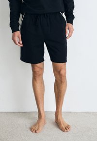 Sorte bomullsshorts med elastisk midjebånd og snøring, med en avslappet passform og ingen synlige mønstre eller detaljer.