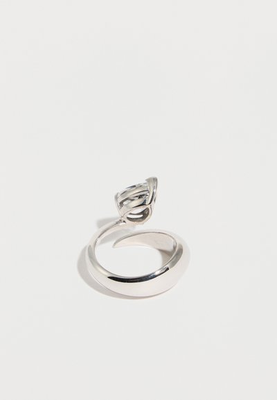 Ανοιχτό ασημένιο δαχτυλίδι με στριφτό στήριγμα που κρατάει ένα διαφανές στρογγυλό πολύτιμο λίθο, εμφανιζόμενο σε λευκό φόντο.