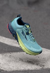 Teal og limegrønn løpesko med teksturert mesh-overdel, Vibram såle og en komfortabel, chunky design. Har reflekterende detaljer.