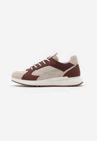 Zapatillas con un upper de ante y cuero en tonos beige y marrón, con cordones blancos, una suela texturizada y un acento rosa en el talón.