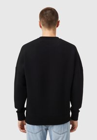Sudadera negra con cuello redondo, ajuste holgado, mangas largas, puños y dobladillo acanalados; textura suave, perfecta para uso casual.