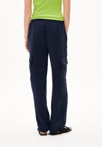 Pantalons cargo bleu marine avec deux poches latérales, taille élastique et coupe décontractée ; le tissu semble léger et légèrement texturé.