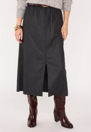 Grijze wollen rok met een voorknit, platte tailleband en plooien. Gecombineerd met bordeauxkleurige heuvelschoenen, wat een gelaagd uiterlijk creëert.