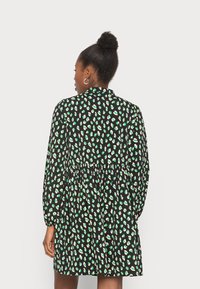 Vestido preto com um padrão de estampa de leopardo verde e branco, mangas longas, cintura franzida e saia rodada. Textura de tecido suave.